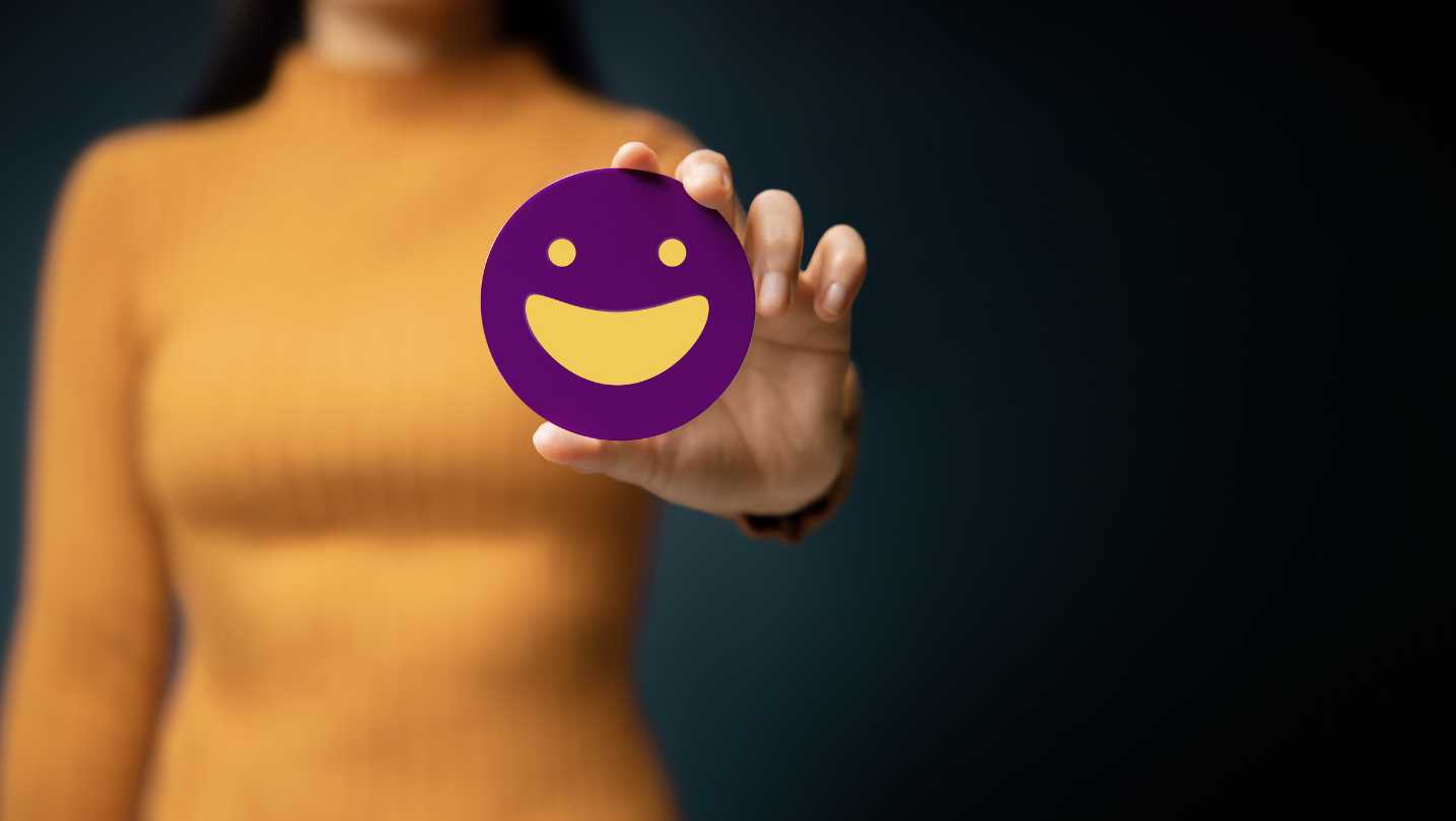 A woman blurred in the background holding a happy smiley.